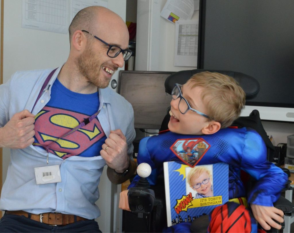 Teacher with shirt open so you can see superman vest and young boy in superman fancy dress looking at him. Newcastle Charity of the Year story. 