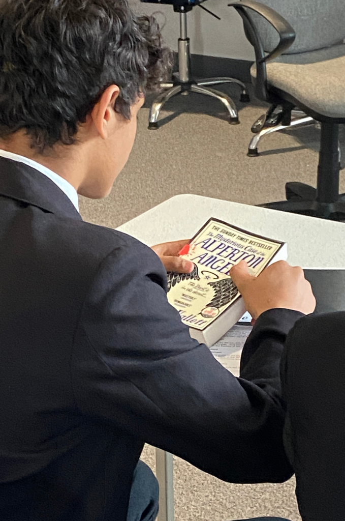 Student holding the book 'Alperton Angels' by Janice Hallett