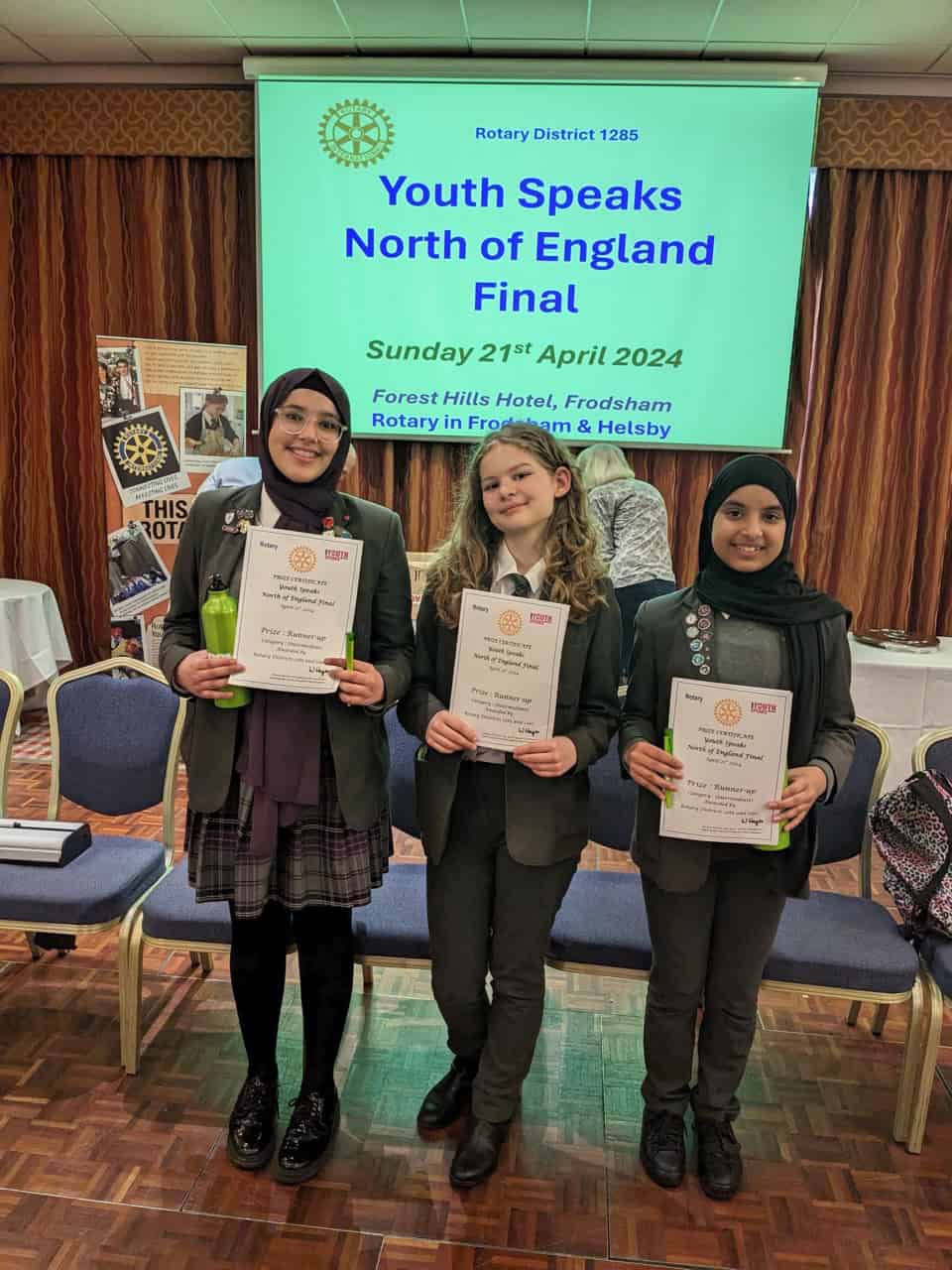 Three students from Laurus Cheadle Hulme smile as they hold their certificates which they received as the Intermediate Runners Up of the Rotary Youth Speaks North of England Final 2024.