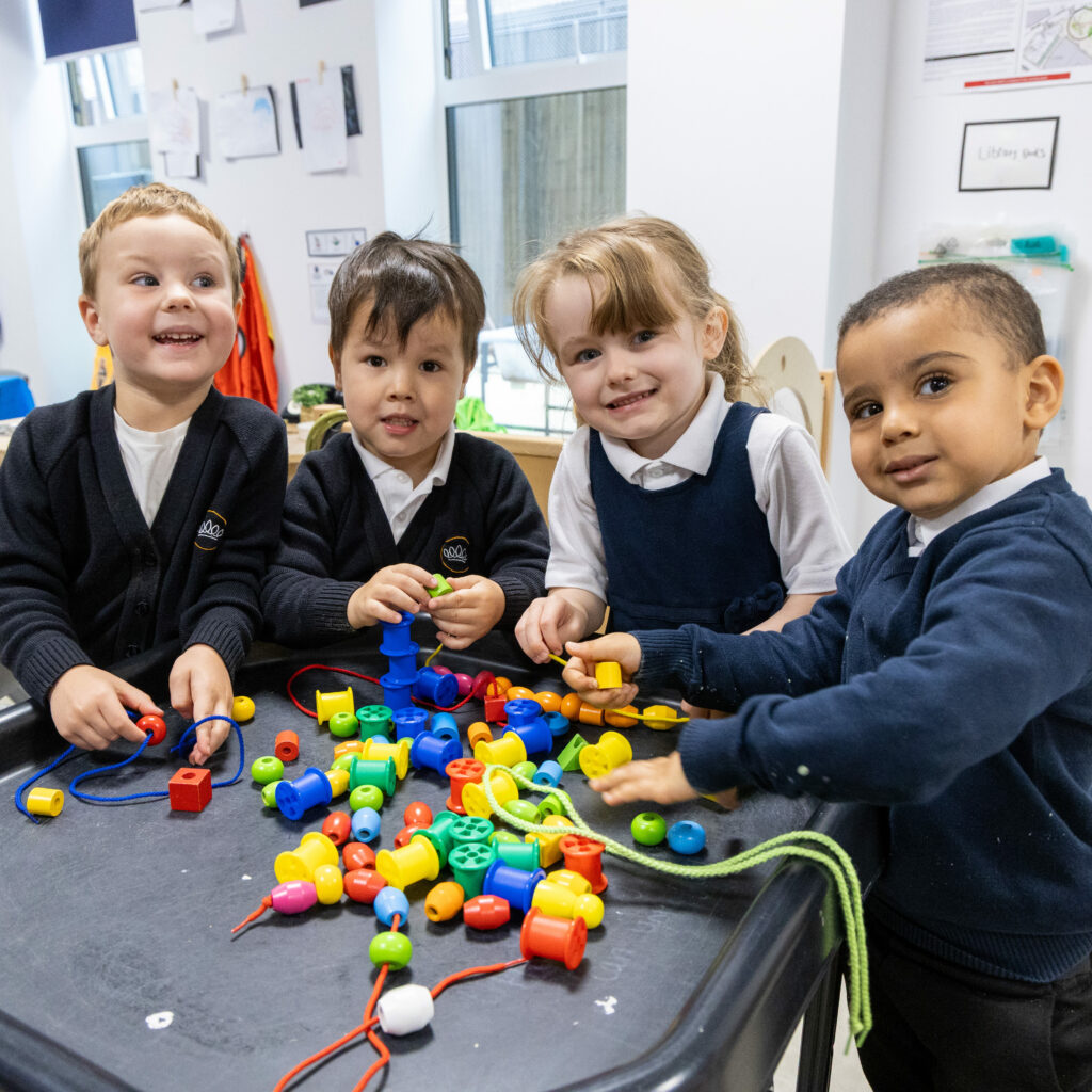 Children at Crown Street Pre School play with colourful beads and threads.