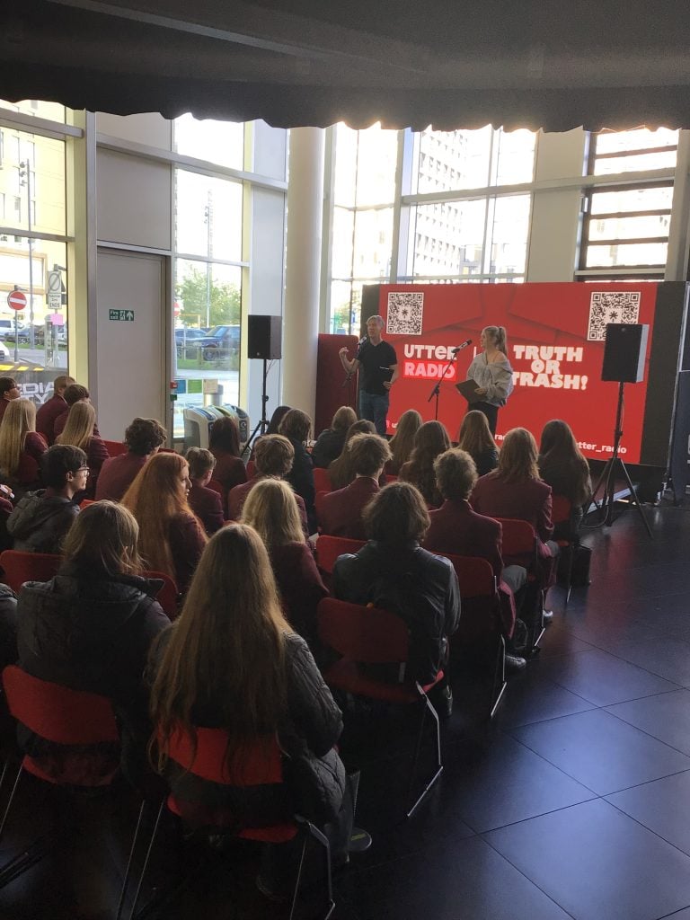 An audience of students from Hazel Grove High School sit and listen to a radio workshop and play 'Truth or Trash'