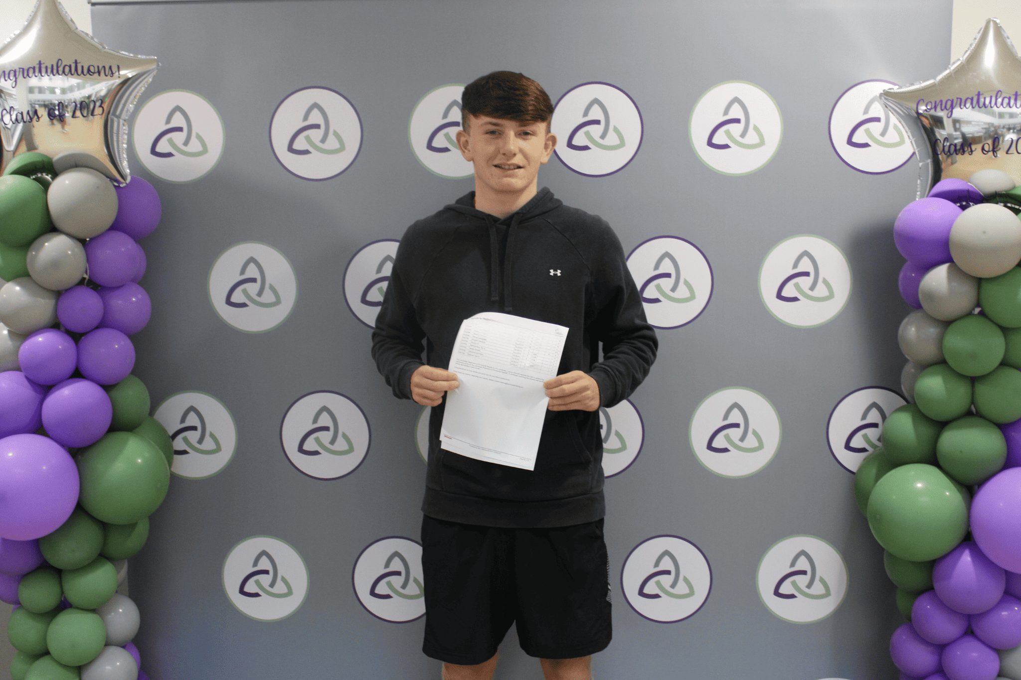 Issac stands proudly holding his GCSE results at Laurus Ryecroft