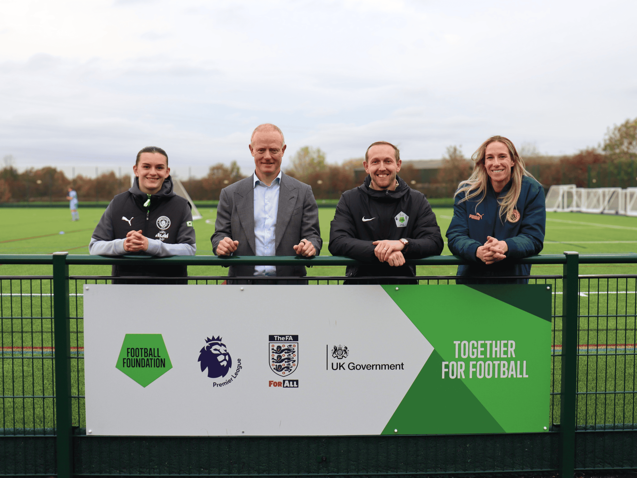 Lily Murphy, Andrew Law, Liam Devlin and Karen Bardsley stand on the new 3g pitch at Laurus Ryecroft, behind a sign for the Football Foundation