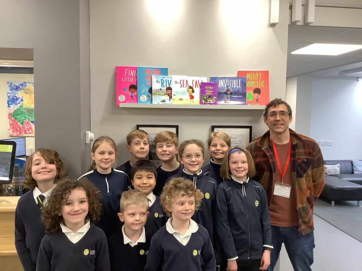 Image of GB pupils and Tom Percival infront of bookshelf.