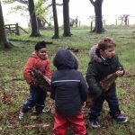Children in the woods carrying logs