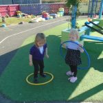 Children in playground playing with hula hoops