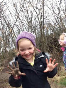 Child smiling with muddy hands
