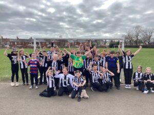 Group of children from NCEA James Knott with their Newcastle football tops on in black and white.