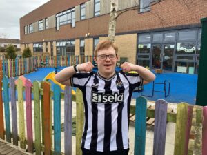 Group of children from NCEA Castle with their Newcastle football tops on in black and white.