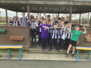 Group of children from NCEA Thomas Bewick with their Newcastle football tops on in black and white.