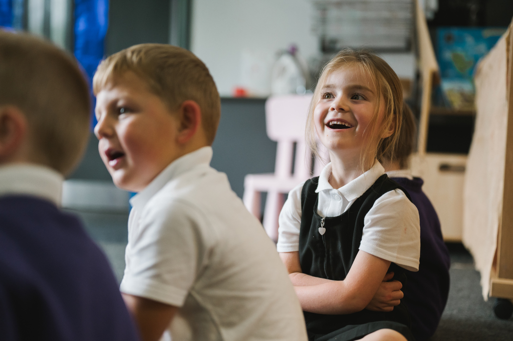 Jack Christophers smiling towards pupil with pen in hand.