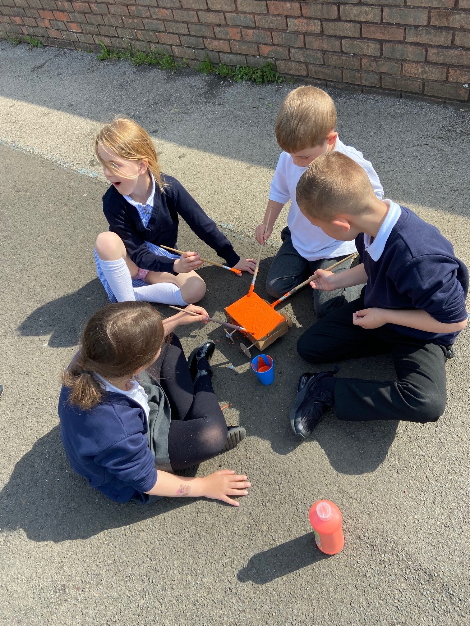 Children making their model cars in a group outside