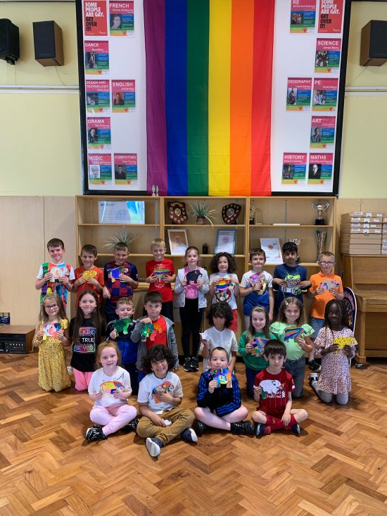 Year 2 children showing off their Elmer work under the rainbow flag