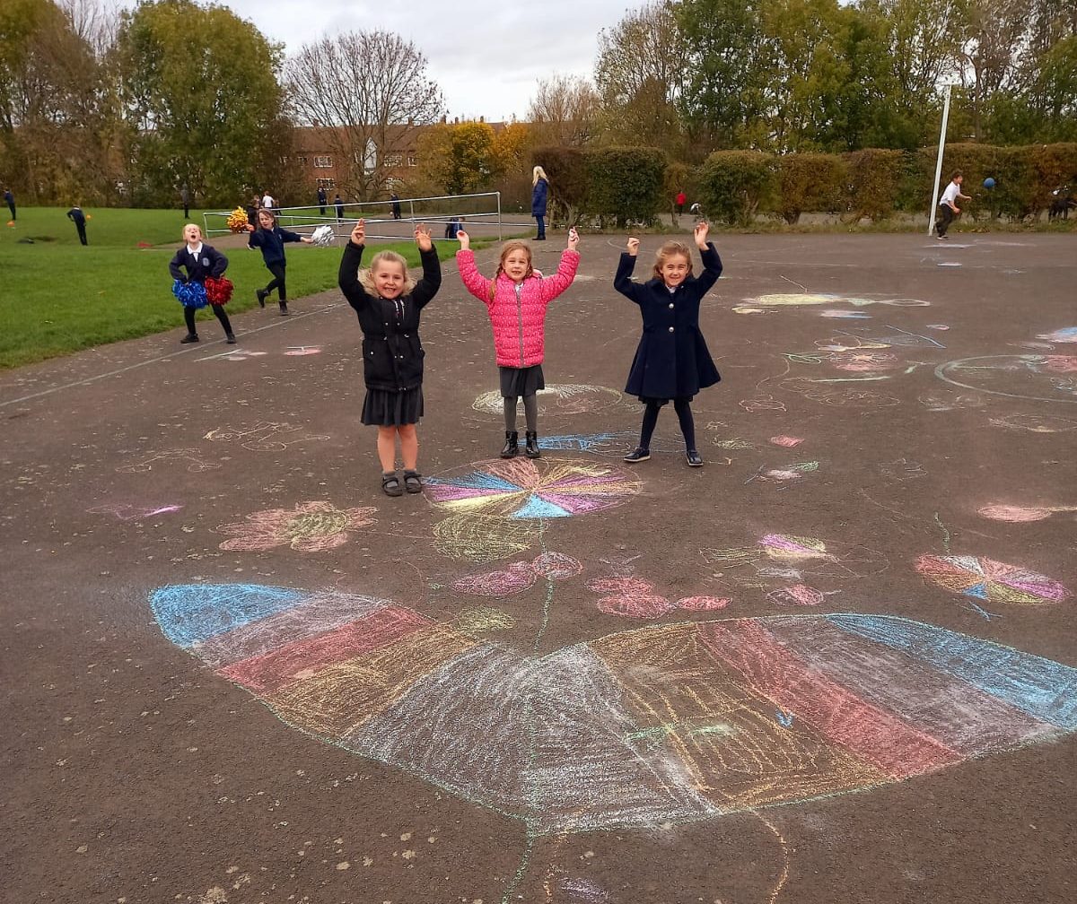 KS1 children enjoying using the chalks to draw during their lunch break