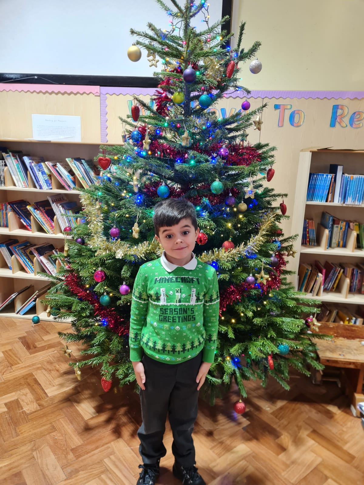 A KS1 child in front of the Christmas tree