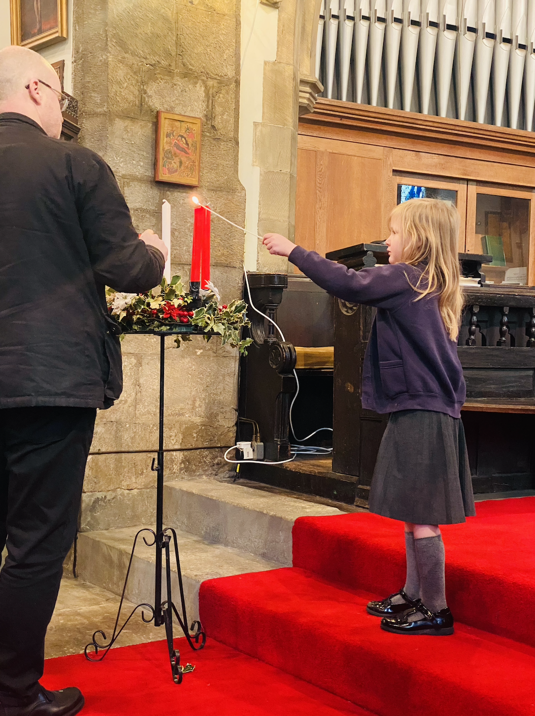 A child helping Rev. Paul light the candles