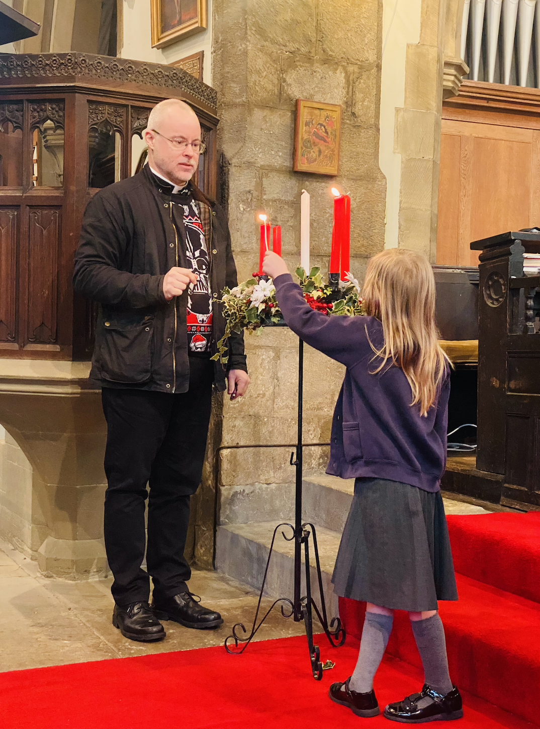 A child helping Rev. Paul light the candles