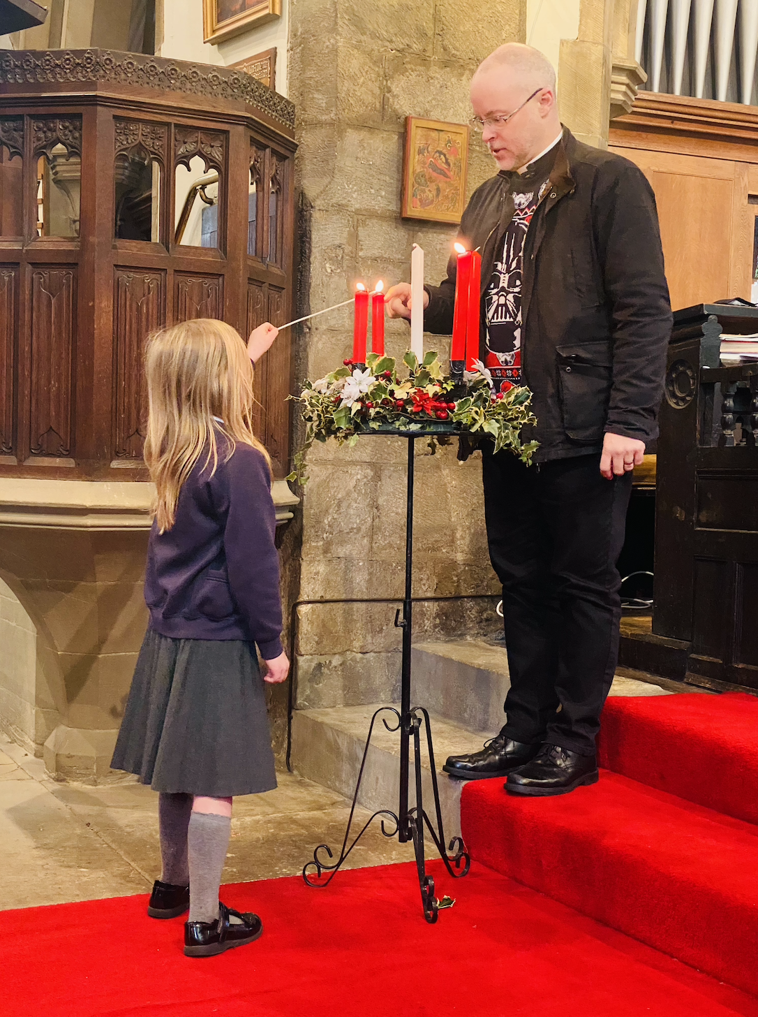 A child helping Rev. Paul light the candles
