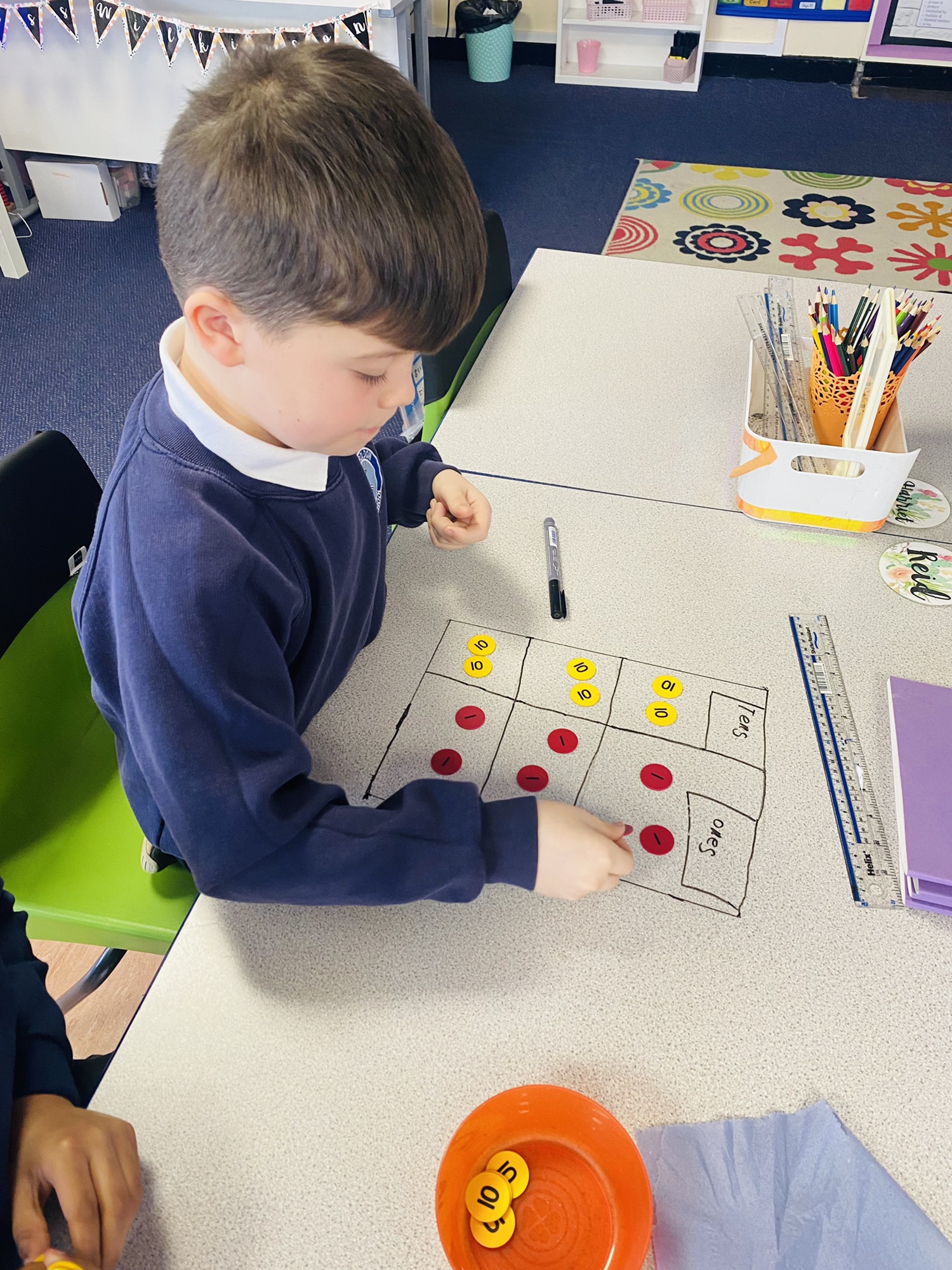 Children solving division problems using place value charts on the tables