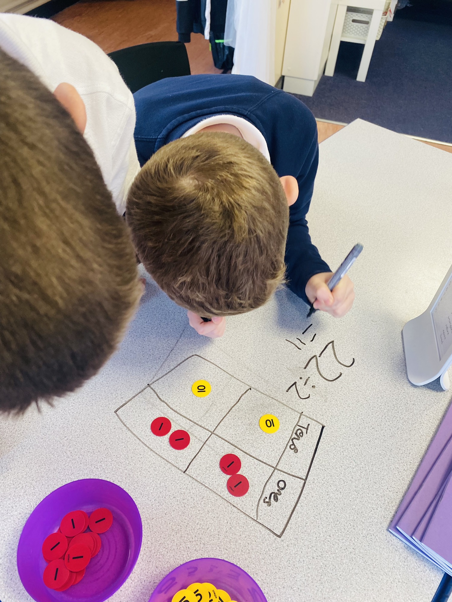 Children solving division problems using place value charts on the tables