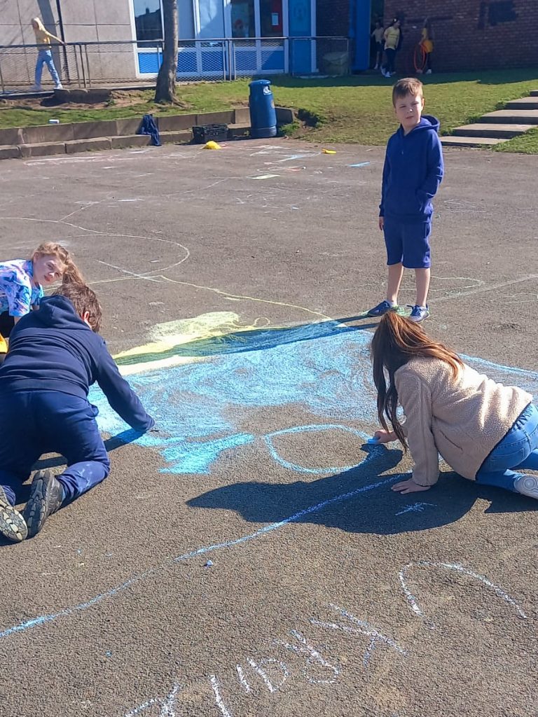Children drawing Ukraine flags in chalk during lunchtime