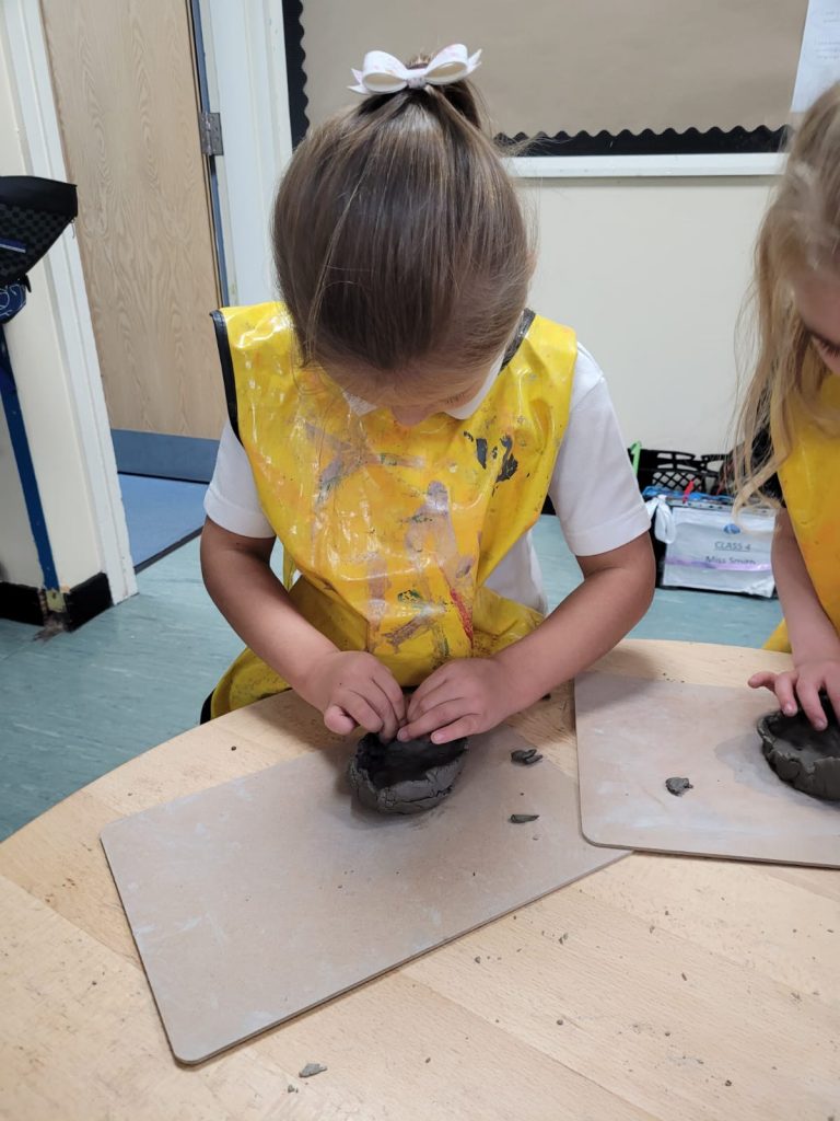 Year 1 children creating their clay pots