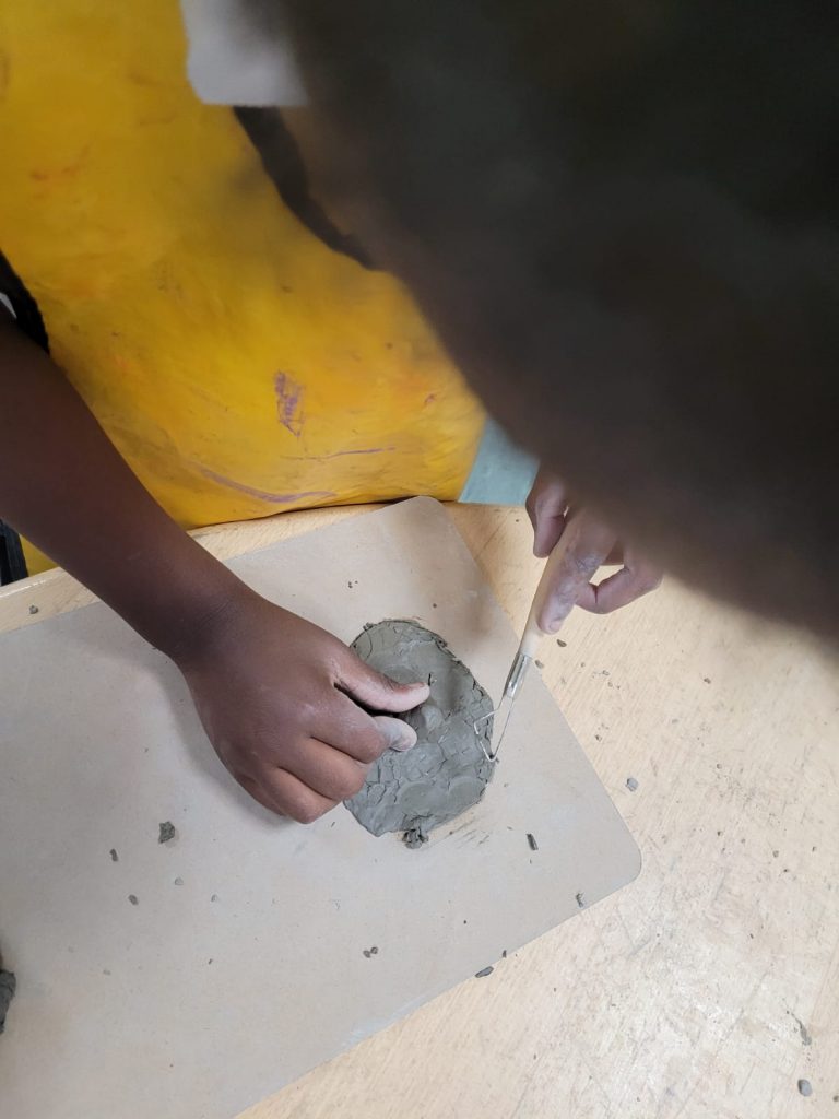 Year 1 children creating their clay pots