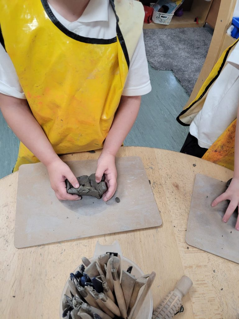 Year 1 children creating their clay pots